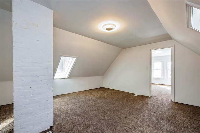 additional living space featuring carpet floors and lofted ceiling with skylight