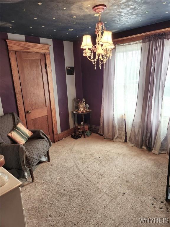 unfurnished room with carpet and a chandelier