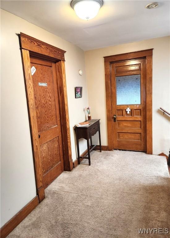 doorway to outside with baseboards and carpet floors