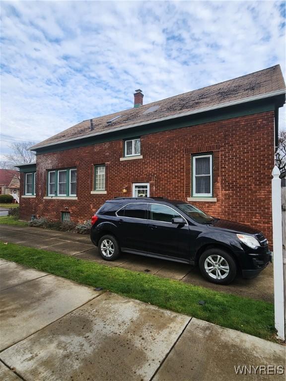 view of home's exterior with brick siding and a chimney