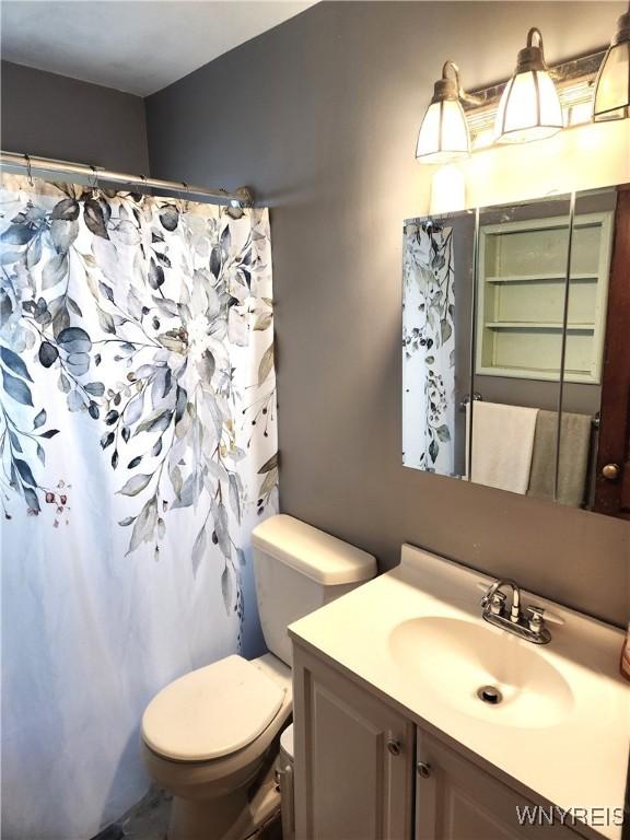 bathroom featuring toilet, vanity, and a shower with curtain