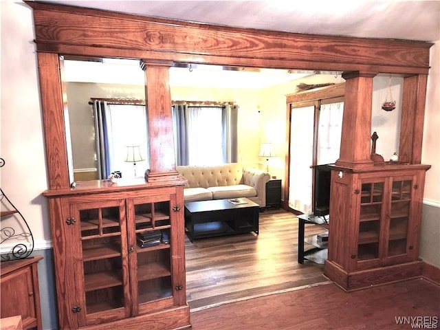 sitting room featuring wood finished floors, baseboards, and decorative columns