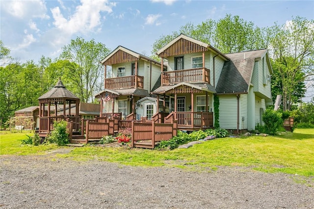 view of front facade featuring a gazebo, a front lawn, a shingled roof, and a balcony