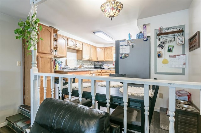 kitchen with open shelves, light countertops, decorative backsplash, light brown cabinetry, and freestanding refrigerator