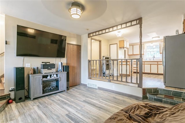 living area featuring visible vents, baseboards, and wood finished floors