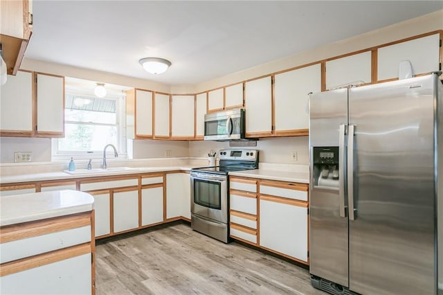 kitchen featuring light countertops, appliances with stainless steel finishes, a sink, and light wood-style flooring