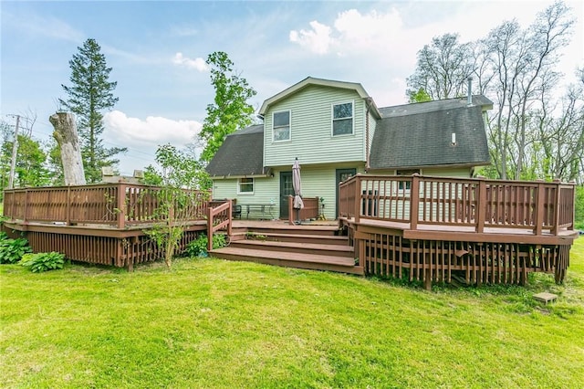 rear view of property featuring a shingled roof, a yard, and a wooden deck