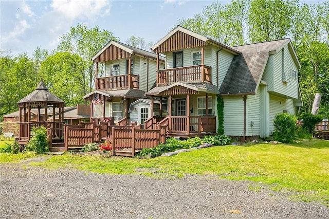 view of front of house with a gazebo, a front lawn, a shingled roof, and a balcony