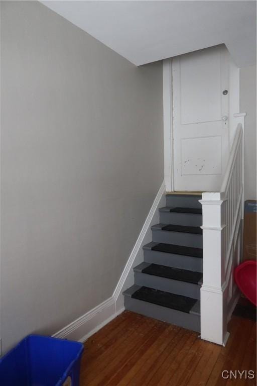 staircase featuring baseboards and wood finished floors