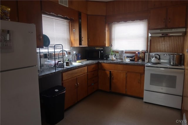 kitchen featuring under cabinet range hood, white appliances, a sink, visible vents, and dark countertops