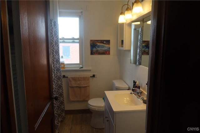 bathroom with toilet, wood finished floors, and vanity