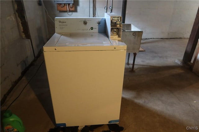 clothes washing area featuring concrete block wall, washer / clothes dryer, and laundry area