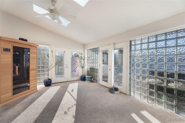 exercise room featuring carpet, french doors, vaulted ceiling with skylight, and ceiling fan