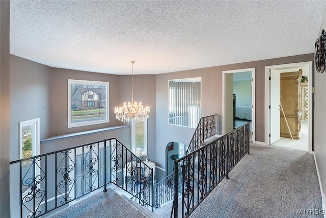 hallway featuring a healthy amount of sunlight, carpet flooring, an upstairs landing, and an inviting chandelier