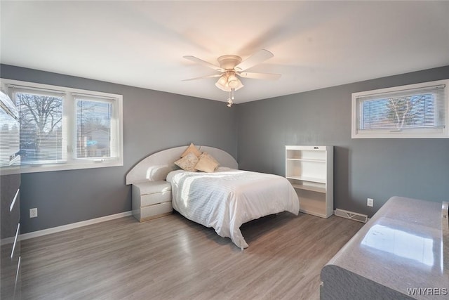 bedroom with ceiling fan, wood finished floors, visible vents, and baseboards