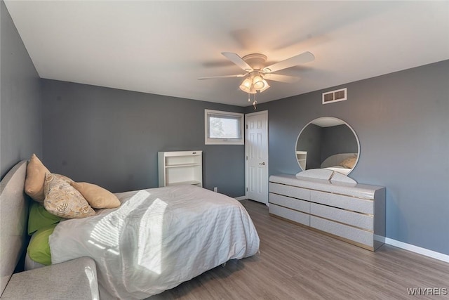 bedroom with a ceiling fan, baseboards, visible vents, and wood finished floors