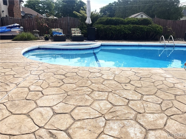 view of pool with a patio area, fence, a fenced in pool, and an in ground hot tub