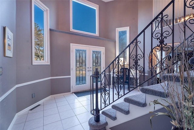 entryway featuring stairs, french doors, visible vents, a towering ceiling, and tile patterned floors