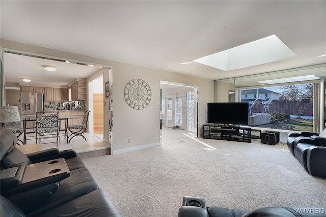 living area with a wealth of natural light, a skylight, light colored carpet, and baseboards