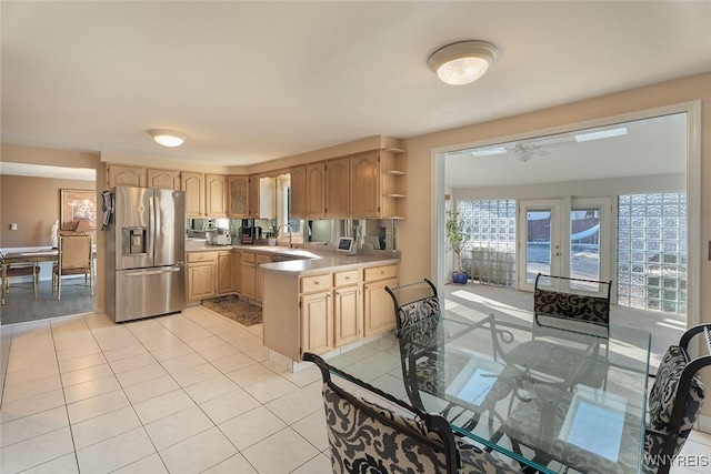 kitchen with light tile patterned floors, light countertops, light brown cabinets, a peninsula, and stainless steel fridge with ice dispenser