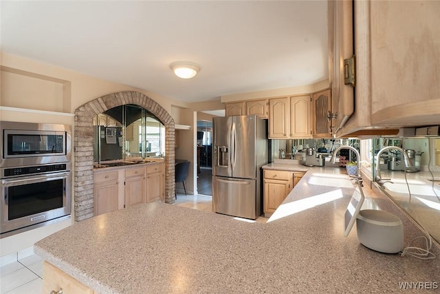 kitchen with appliances with stainless steel finishes, a sink, light countertops, light brown cabinetry, and a wealth of natural light