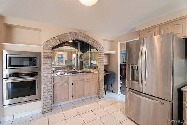 kitchen featuring light tile patterned floors, light brown cabinets, stainless steel appliances, and light countertops