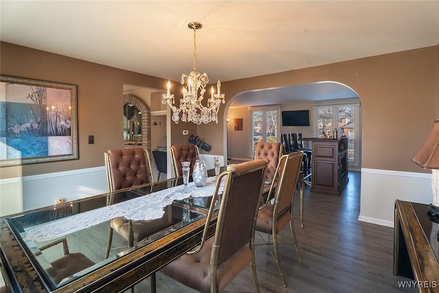 dining room featuring arched walkways, baseboards, dark wood finished floors, and an inviting chandelier