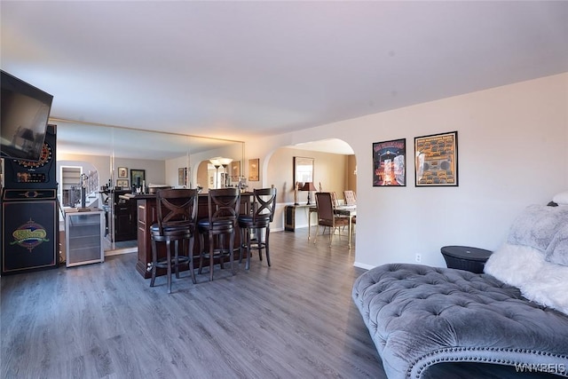 living area featuring dark wood-style floors, baseboards, wine cooler, and arched walkways