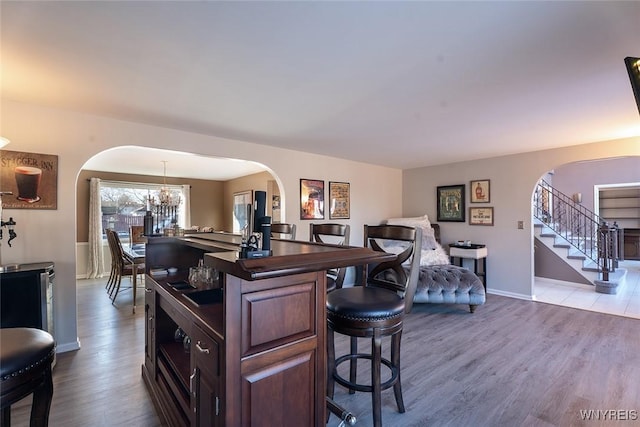 kitchen with a breakfast bar, arched walkways, dark countertops, and wood finished floors