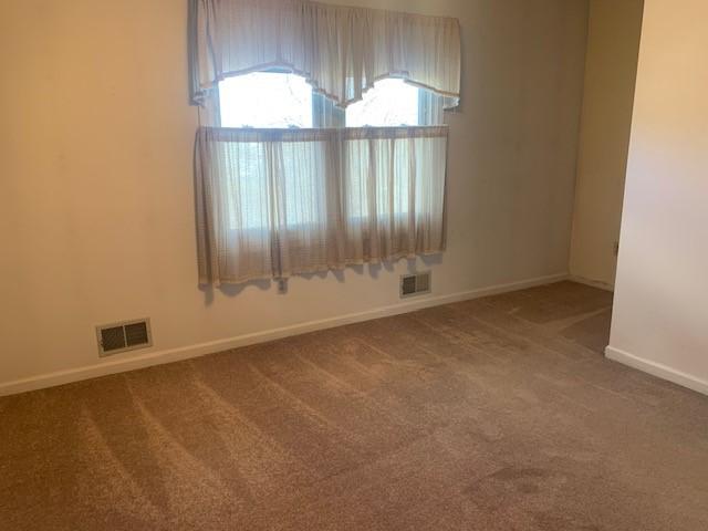 empty room featuring baseboards, visible vents, and carpet flooring