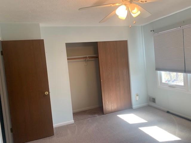 unfurnished bedroom featuring carpet, a closet, visible vents, a ceiling fan, and baseboards