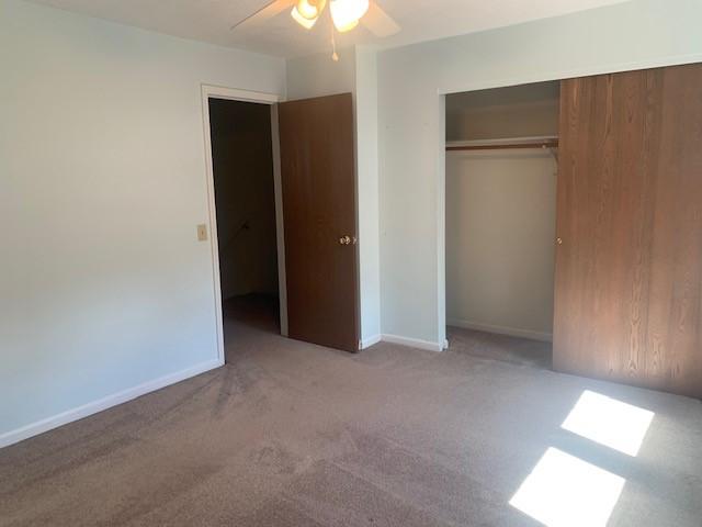 unfurnished bedroom featuring a closet, carpet, a ceiling fan, and baseboards