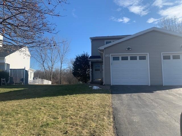 view of side of home featuring driveway, an attached garage, and a lawn