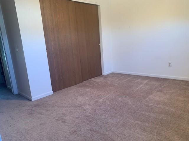 unfurnished bedroom with a closet, carpet flooring, and baseboards