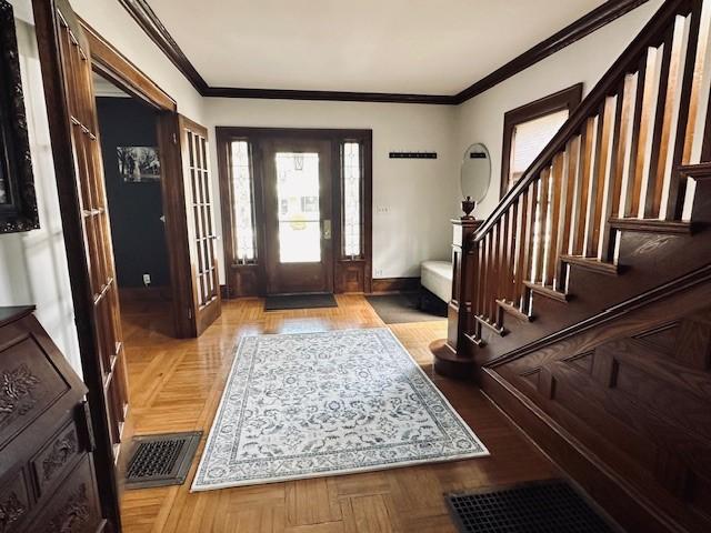 foyer entrance with stairs, baseboards, visible vents, and ornamental molding