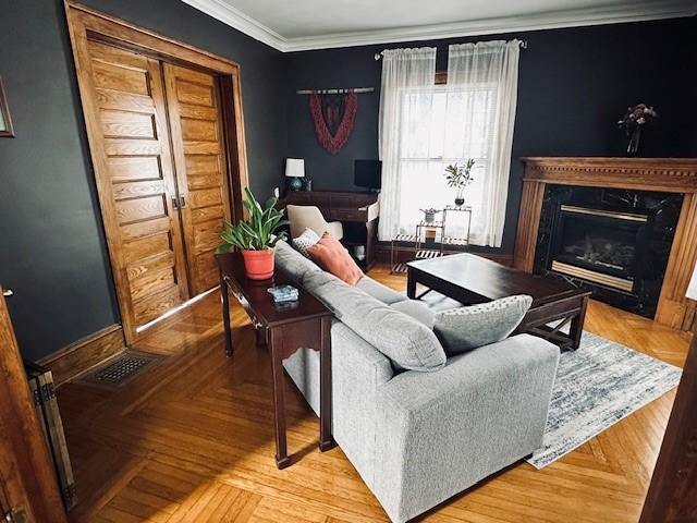 living room with a high end fireplace, visible vents, crown molding, and baseboards