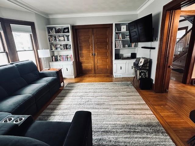 living area with stairway, wood finished floors, and crown molding