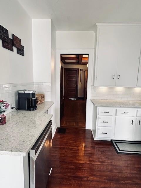 kitchen with stainless steel dishwasher, white cabinets, dark wood finished floors, and tasteful backsplash