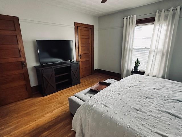 bedroom featuring a ceiling fan, wood finished floors, and baseboards