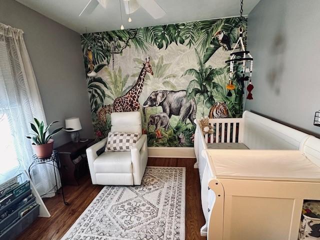 bedroom featuring wallpapered walls, a ceiling fan, baseboards, and wood finished floors