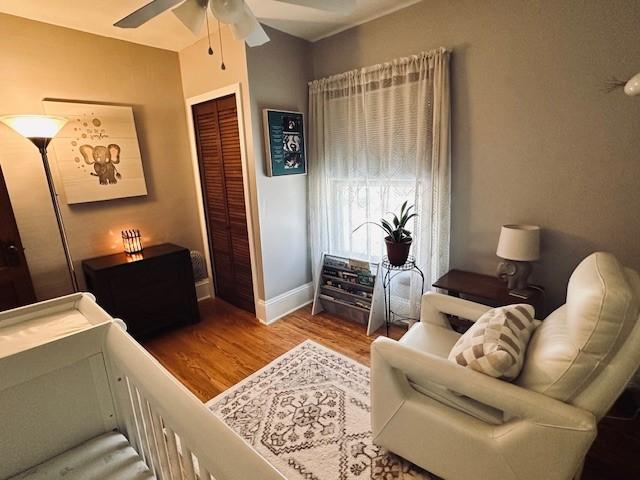 bedroom featuring a closet, baseboards, a ceiling fan, and wood finished floors