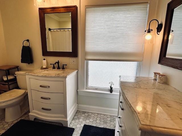 bathroom with toilet, vanity, and baseboards