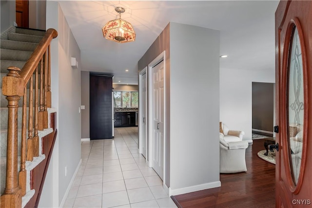 hall featuring baseboards, stairway, and recessed lighting