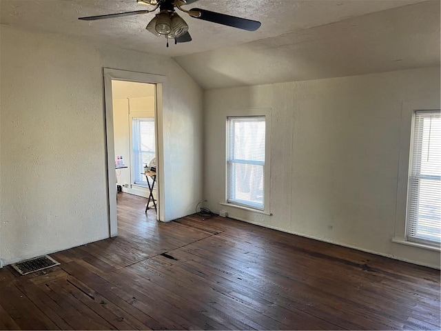 unfurnished room with a wealth of natural light, visible vents, dark wood-type flooring, and a textured wall