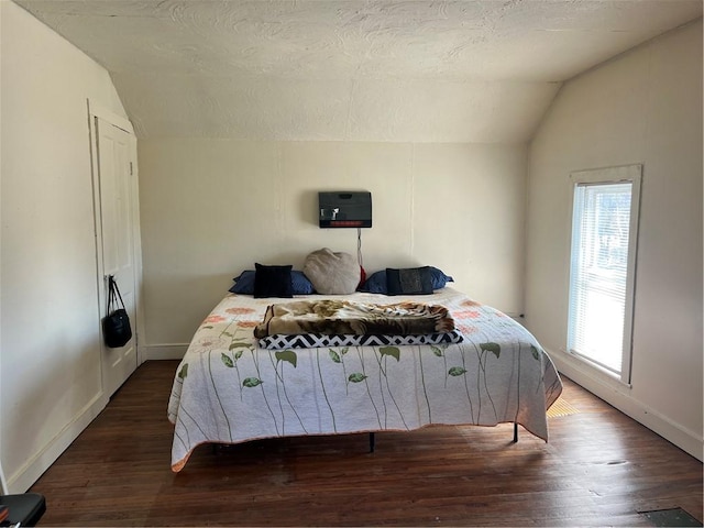 bedroom with vaulted ceiling, baseboards, and wood finished floors