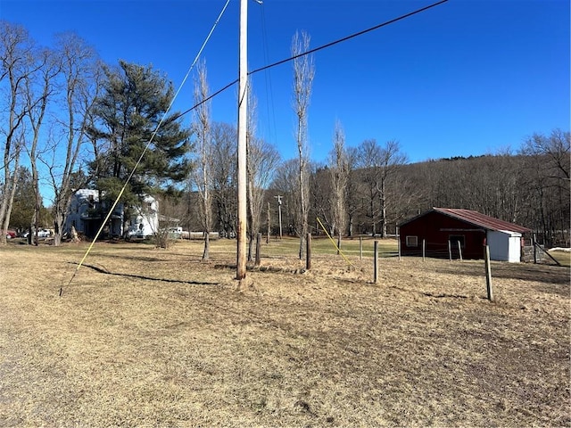 view of yard featuring an outbuilding and a view of trees