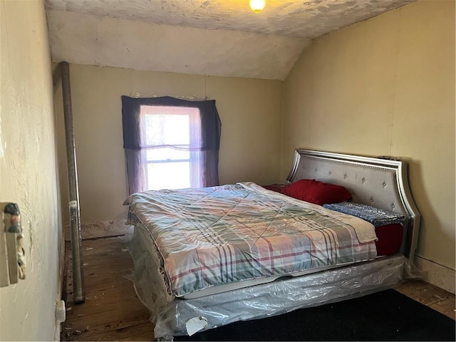 bedroom featuring wood-type flooring, vaulted ceiling, and a textured ceiling