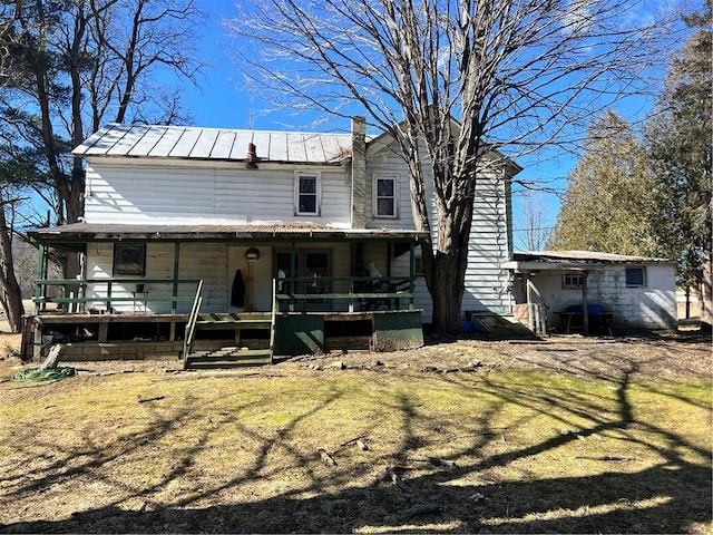 back of house featuring metal roof and a chimney