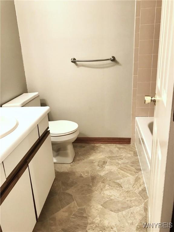 bathroom with toilet, vanity, and baseboards