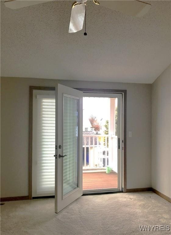 doorway to outside featuring carpet flooring, a textured ceiling, and baseboards